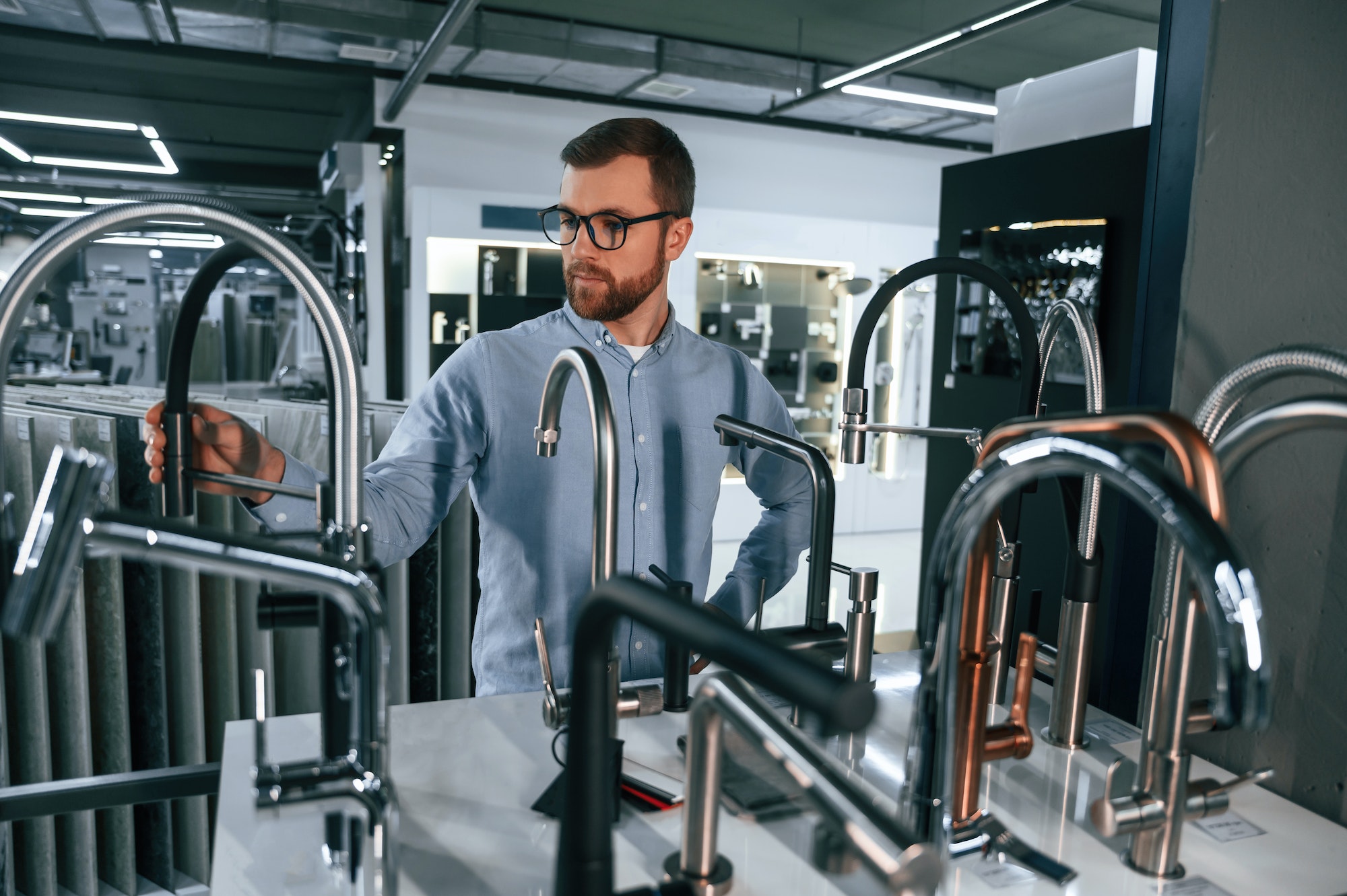 A large selection of water faucets. Man chooses a products in a sanitary ware store